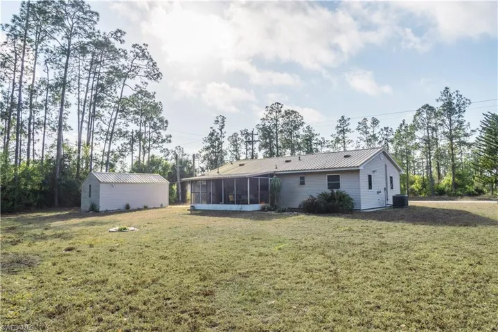 Rear view of property with a sunroom, a yard, and a metal roof
