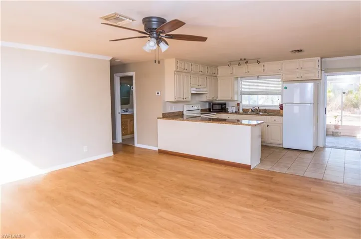 Kitchen with white appliances, crown molding, ceiling fan, a peninsula, and light wood-style flooring