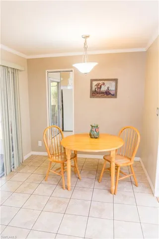 Dining room with crown molding and light tile patterned floors