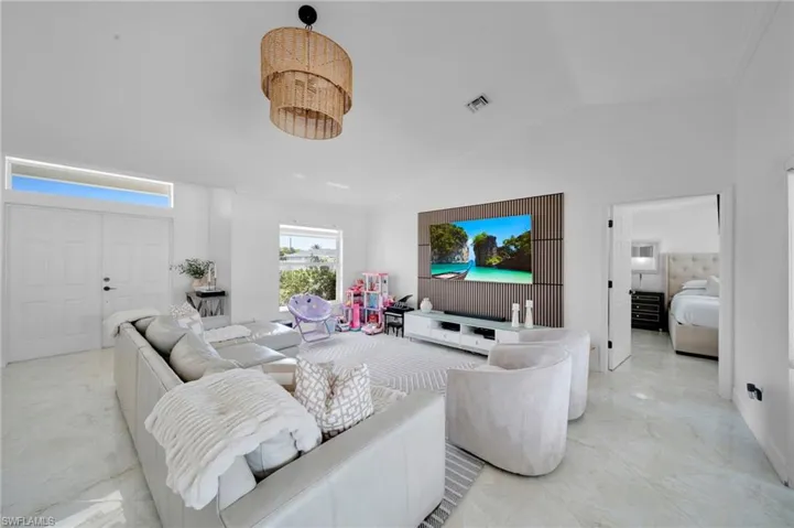 Living room with light marble finish floors, vaulted ceiling, and ornamental molding