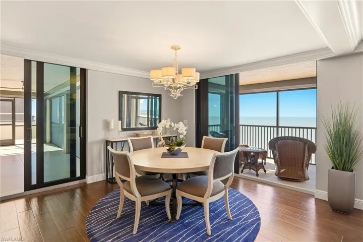 Dining area featuring floor to ceiling windows, wood finished floors, a water view, a chandelier, and crown molding