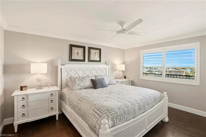 Bedroom with ornamental molding, ceiling fan, and dark wood-style flooring