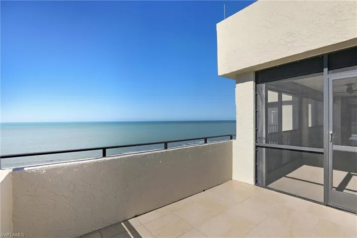 Balcony featuring view of water and beach
