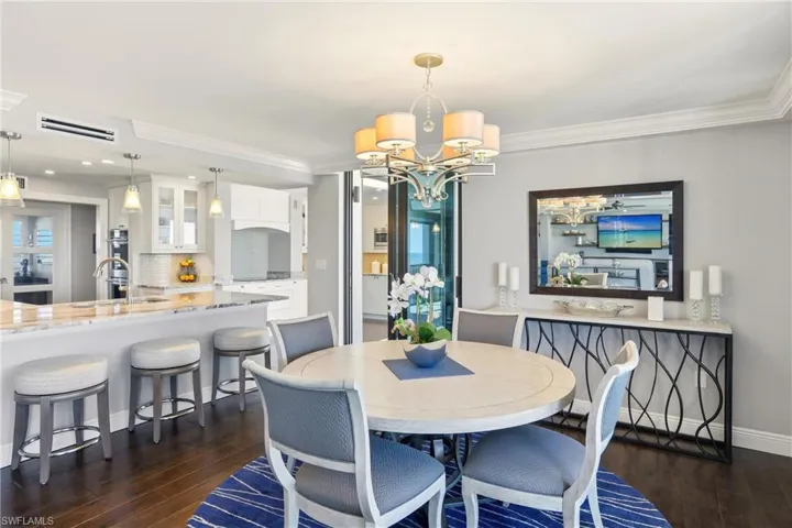 Dining space featuring a chandelier, dark wood finished floors, and ornamental molding