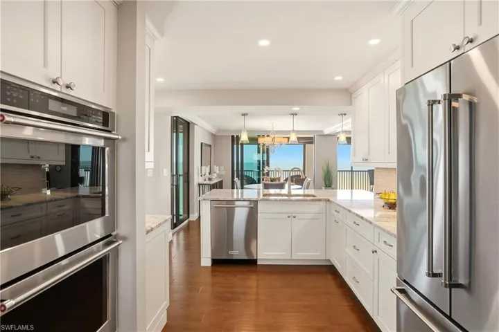 Kitchen with decorative backsplash, appliances with stainless steel finishes, white cabinets, dark wood-style flooring, and recessed lighting