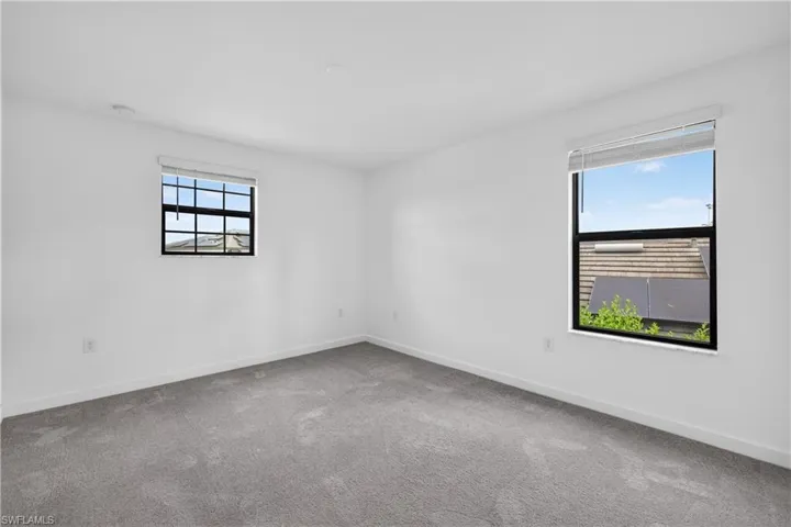 Bright corner bedroom flooded with natural light through dual windows featuring black-framed panes