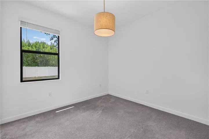 Neutral wall paint paired with gray carpeting and a single window with a roller shade