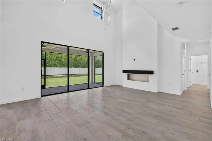 Vaulted ceilings with high windows, wood-finish tile flooring, and a built-in fireplace