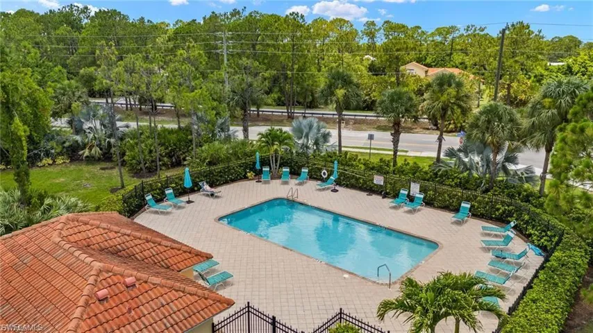 Outdoor swimming pool with a tile deck, perimeter hedge landscaping, and a terracotta tile roof structure