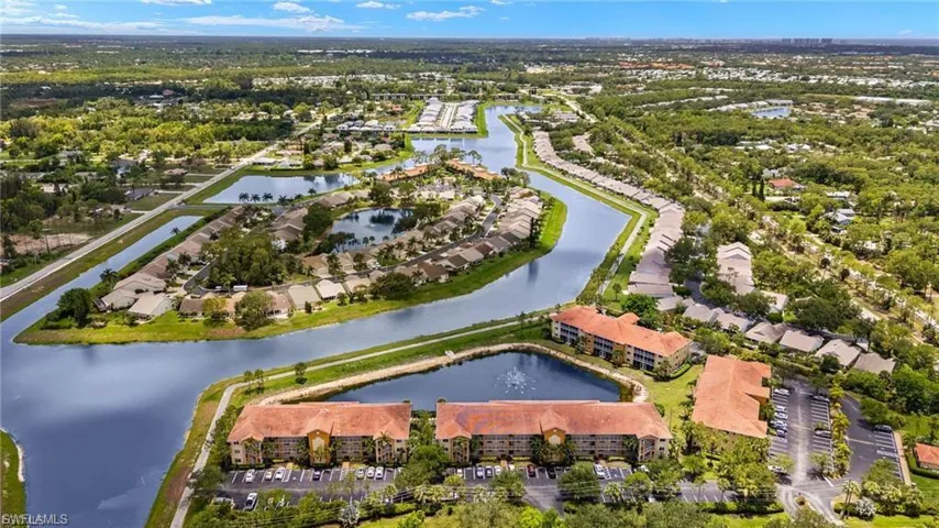Aerial perspective of a multi-building residential complex featuring tile roofing, extensive waterfront canal exposure, and paved parking lots
