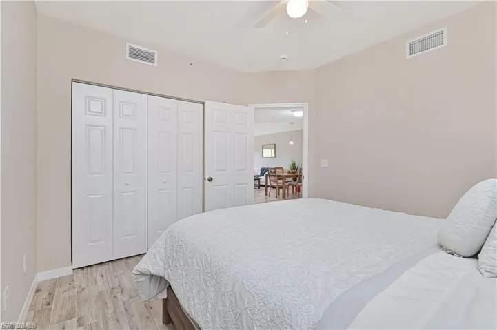 Neutral wall tones, wood-finish flooring, ceiling fan with integrated light fixture, and six-panel closet doors