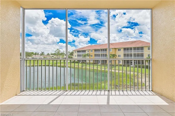 Screened-in patio with tile flooring, aluminum framing, and metal railings, overlooking a pond