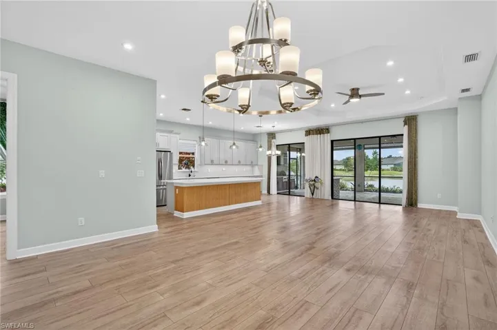 Unfurnished living room featuring a chandelier, light wood-type flooring, recessed lighting, and ceiling fan