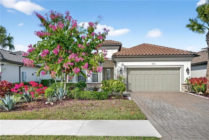 Mediterranean / spanish house with stone siding, stucco siding, decorative driveway, a tile roof, and an attached garage