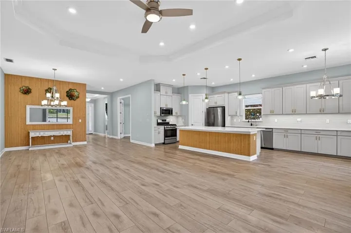 Kitchen with a chandelier, pendant lighting, light countertops, open floor plan, and wooden walls