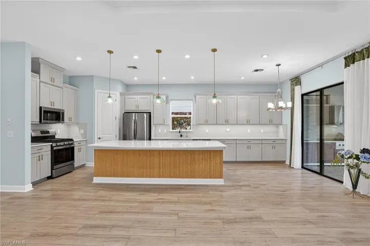 Kitchen featuring appliances with stainless steel finishes, a kitchen island, decorative light fixtures, tasteful backsplash, and recessed lighting