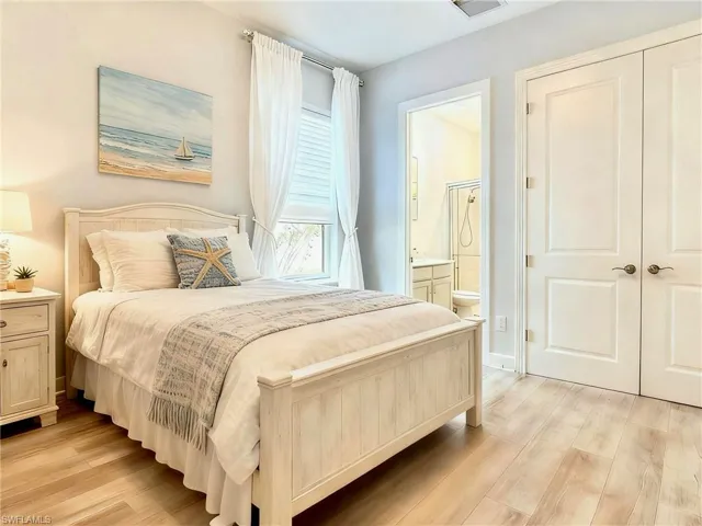 Bedroom with light wood-style floors and ensuite bath