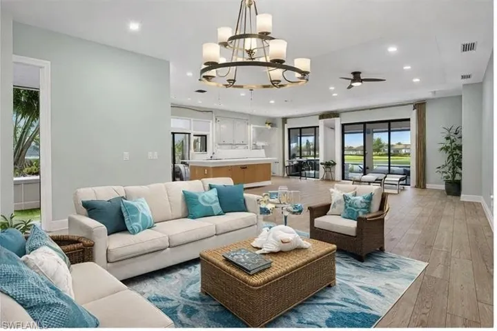 Living area with light wood-style floors, suspended lighting, and a ceiling fan