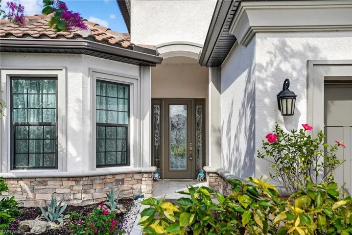 Entrance to property with stone siding, stucco siding, and a tile roof