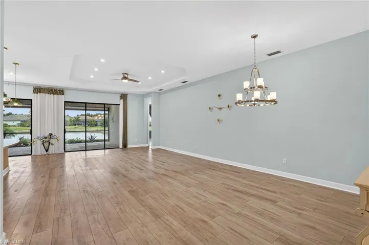 Spare room featuring light wood-style floors, a raised ceiling, recessed lighting, a chandelier, and ceiling fan