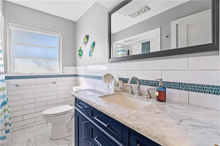 Bathroom featuring vanity, toilet, and tile walls