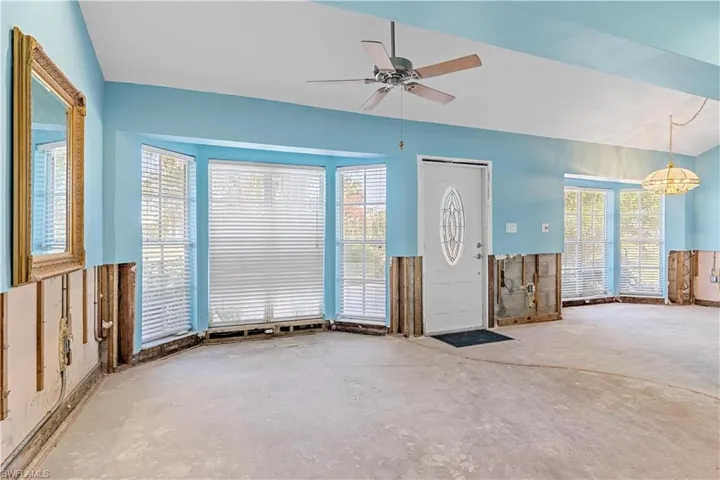 Unfurnished living room featuring plenty of natural light, concrete floors, and ceiling fan with notable chandelier