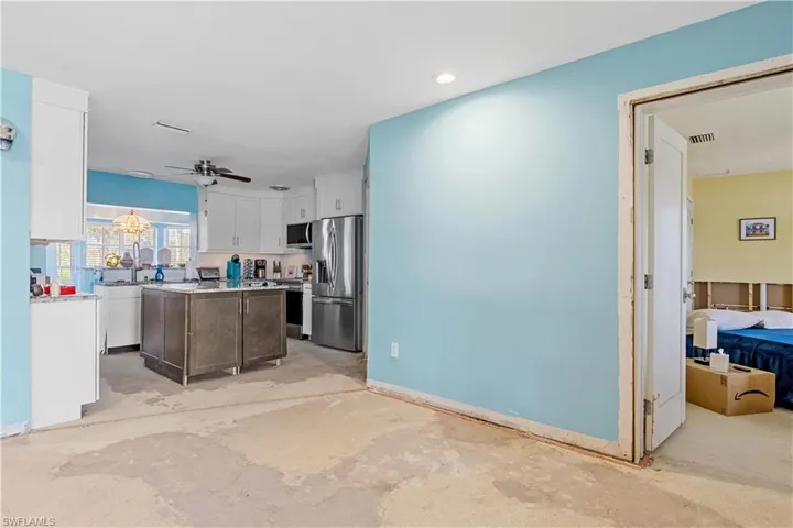 Kitchen with a center island, stainless steel appliances, white cabinetry, and ceiling fan
