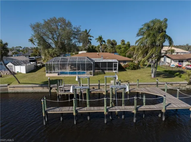 View of dock with a yard, a water view, and a lanai