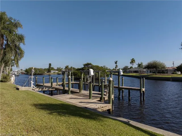 View of dock with a yard and a water view