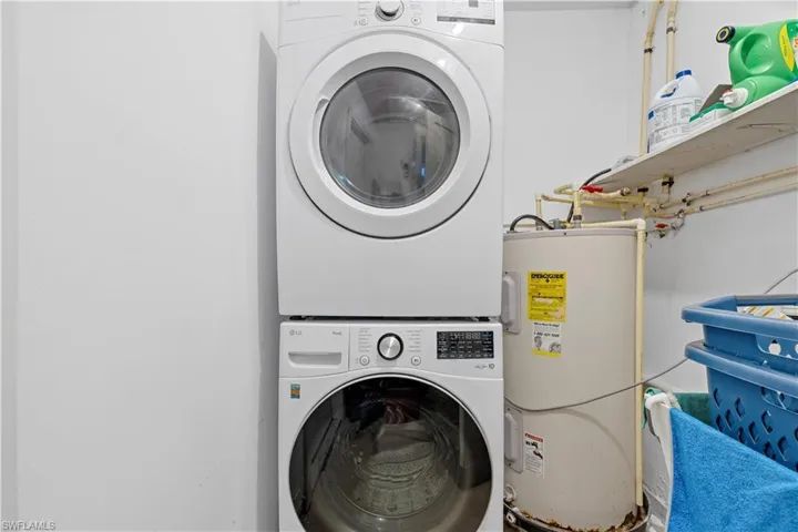 Washroom featuring stacked washer / drying machine and water heater
