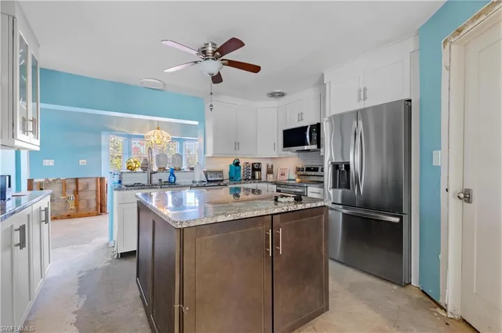 Kitchen featuring a center island, white cabinets, stainless steel appliances, and sink