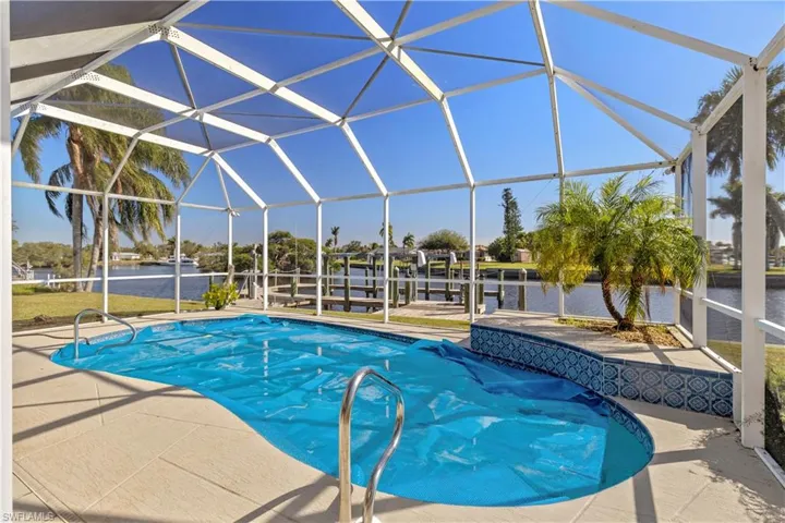 View of pool featuring a water view, glass enclosure, a patio area, and a boat dock