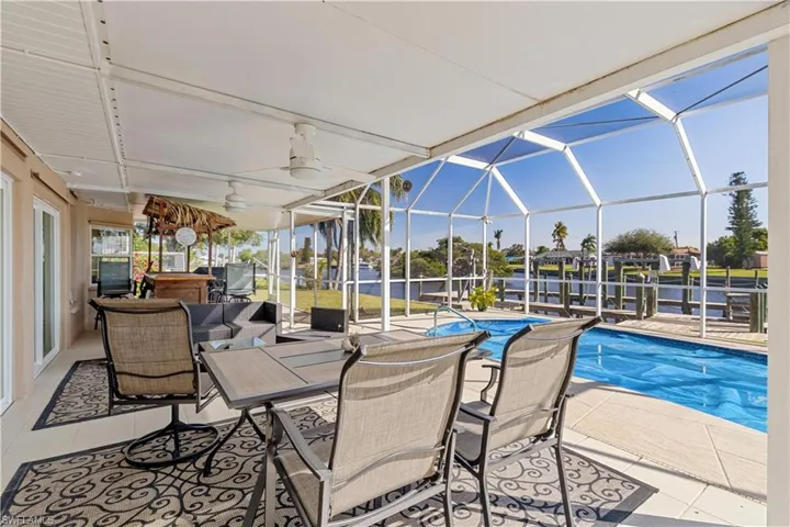 View of swimming pool featuring ceiling fan, a patio, and glass enclosure