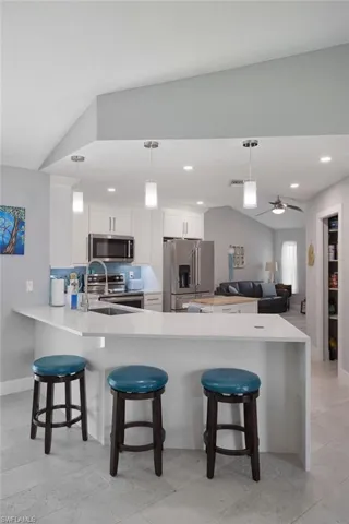Kitchen with shaker cabinets, pendant lighting, waterfall quartz countertops and recessed lighting