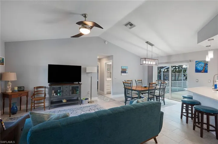 Living room with light tile patterned floors, vaulted ceiling, and ceiling fan