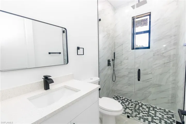Bathroom featuring a marble finish shower and vanity