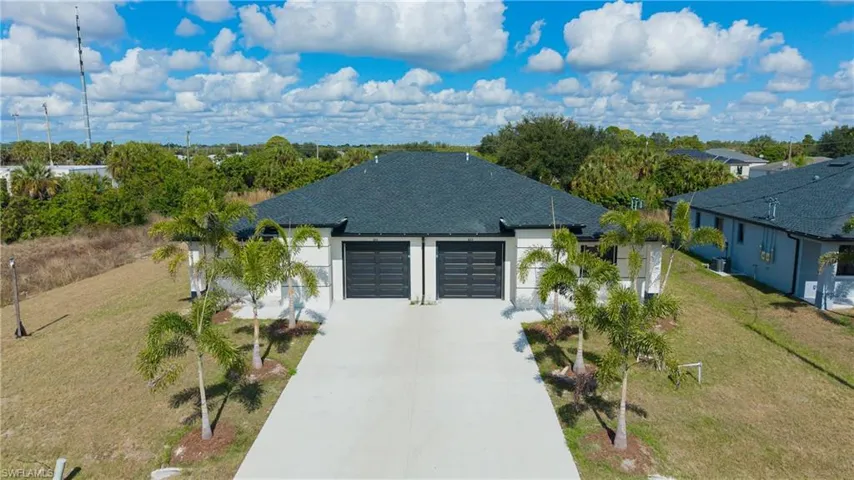 View of front of house featuring a shingled roof, concrete driveway, a garage, stucco siding, and a front yard