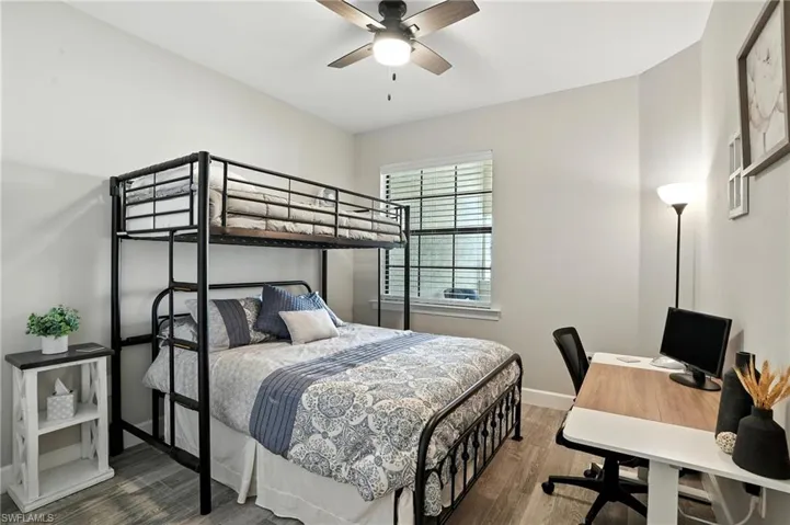 Bedroom with wood finished floors, ceiling fan, and an office area
