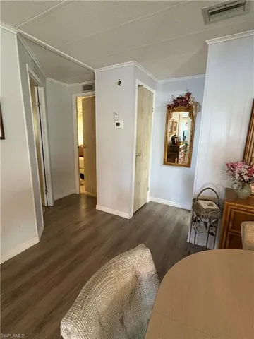 Living room featuring a textured ceiling, dark hardwood / wood-style floors, and crown molding
