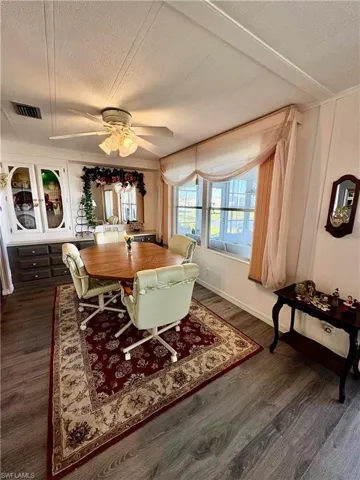 Dining space featuring ceiling fan, dark wood-type flooring, and a textured ceiling