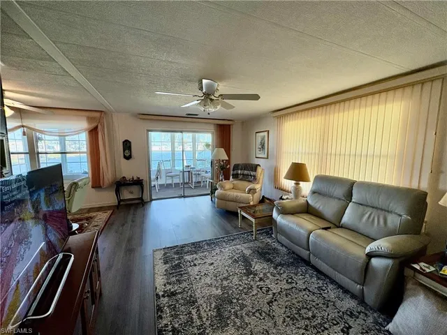 Living room with dark hardwood / wood-style floors, ceiling fan, and a textured ceiling