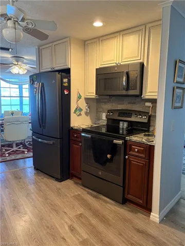 Kitchen with ceiling fan, backsplash, light hardwood / wood-style floors, white cabinets, and appliances with stainless steel finishes