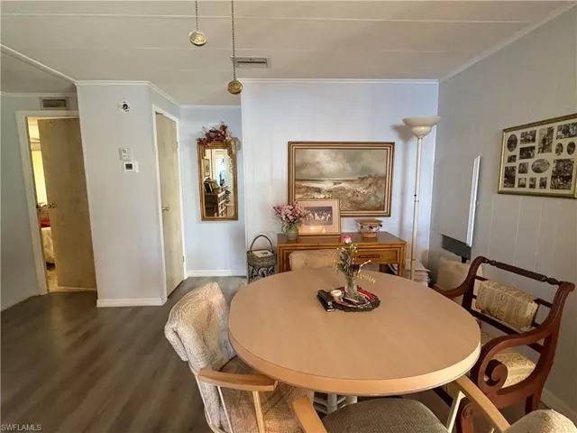 Dining area featuring dark wood-type flooring and ornamental molding