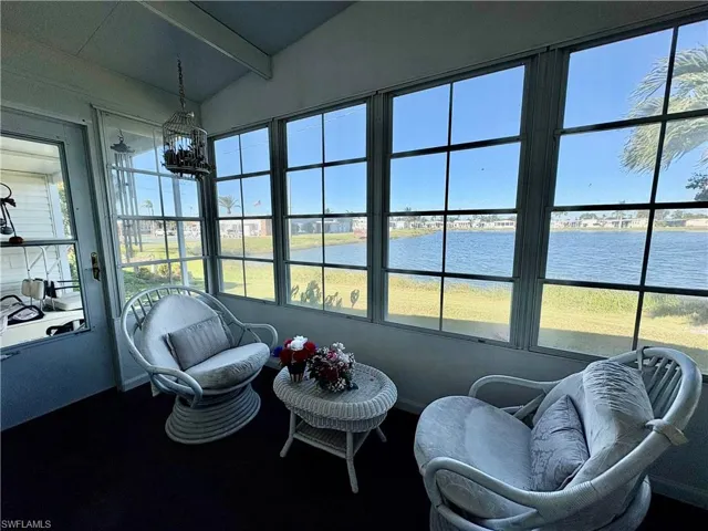 Sunroom featuring lofted ceiling with beams and a water view