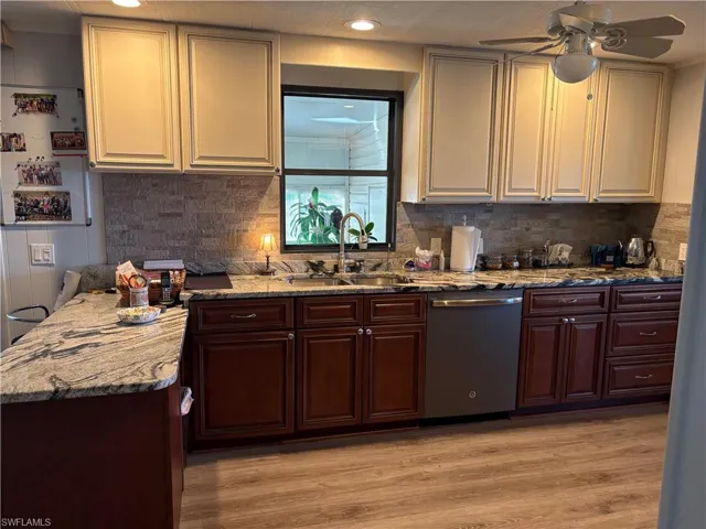 Kitchen with ceiling fan, sink, light hardwood / wood-style flooring, stainless steel dishwasher, and decorative backsplash