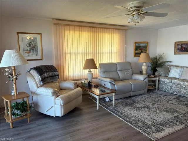 Living room with ceiling fan, dark hardwood / wood-style flooring, and ornamental molding