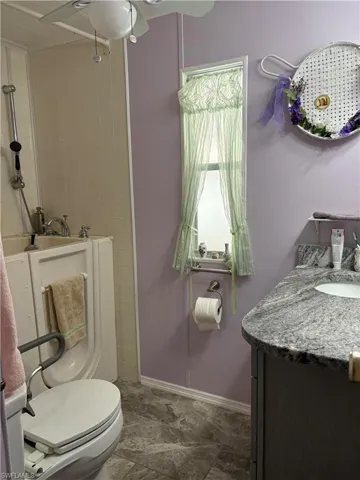 Bathroom featuring vanity, ceiling fan, and toilet