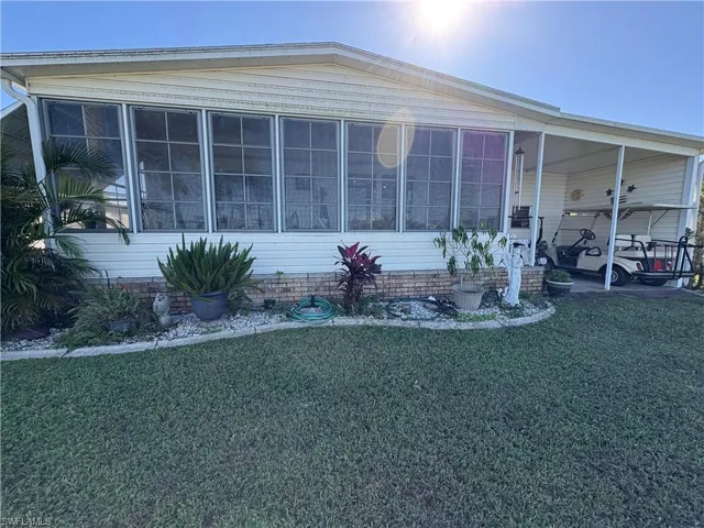 Manufactured / mobile home with a front lawn, a carport, and a sunroom