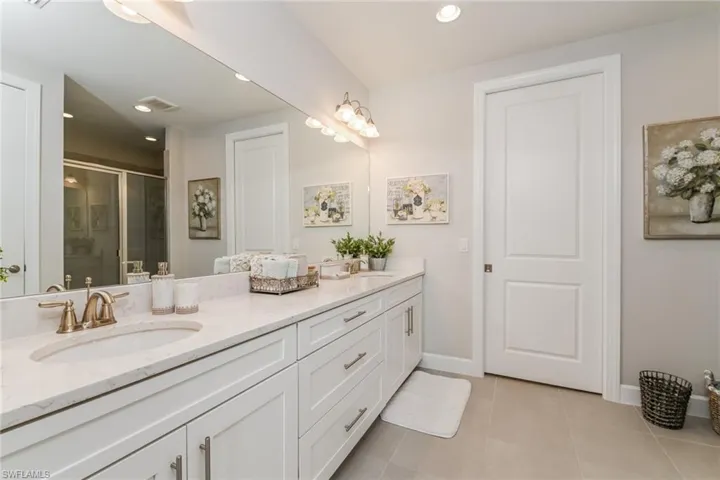 Bathroom featuring double vanity, a shower stall, recessed lighting, and light tile patterned flooring