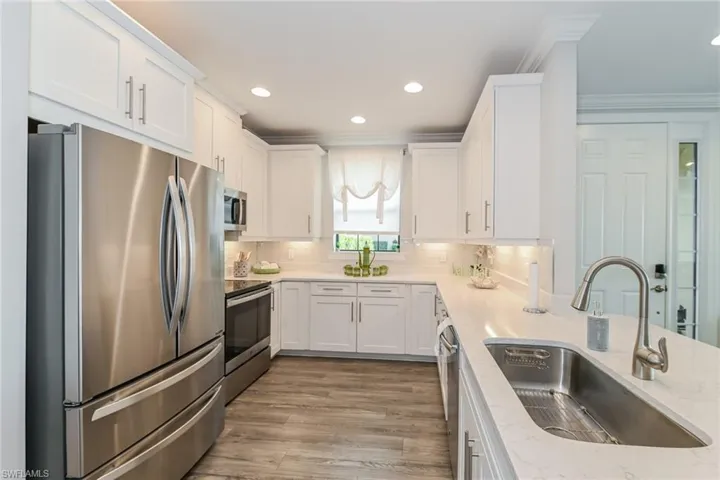 Kitchen featuring appliances with stainless steel finishes, white cabinetry, light stone countertops, recessed lighting, and light wood finished floors